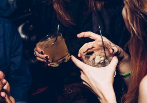 People are holding drinks and laughing in a social setting, indicating a lively, festive atmosphere.