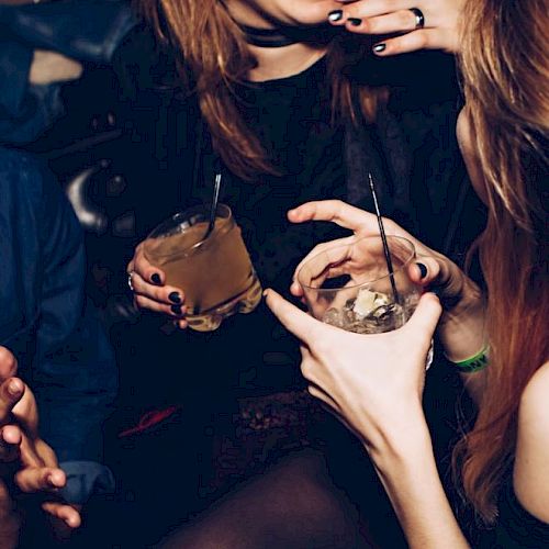People are holding drinks and laughing in a social setting, indicating a lively, festive atmosphere.