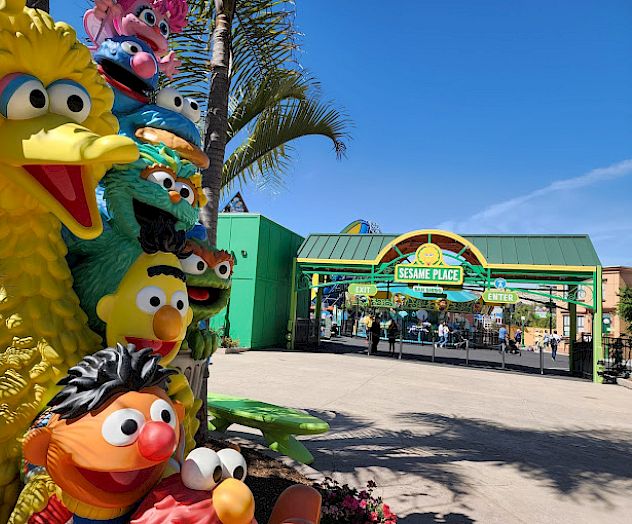 The image shows the entrance to Sesame Place, with a statue of various colorful 